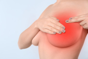 Woman doing breast self-examination on light background. Cancer awareness