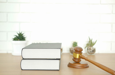 law book & judge gavel near white brick wall. lawyer attorney justice workplace