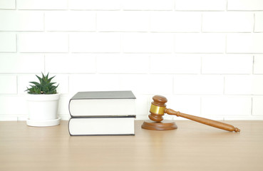 law book & judge gavel near white brick wall. lawyer attorney justice workplace