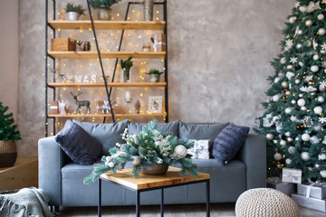 Interior of modern living room with comfortable sofa decorated with Christmas tree and gifts