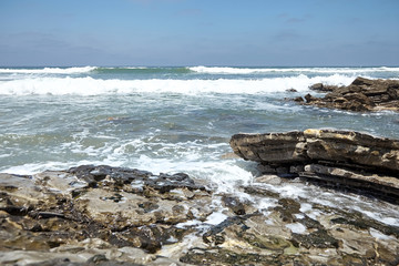 Waves crashing against sharp stones. Ocean shore. Rocky beach