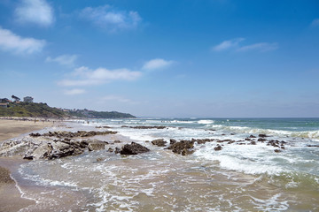Beach of Bidart, France. Sharp stones and ocean water. Sunny summer day with blue sky