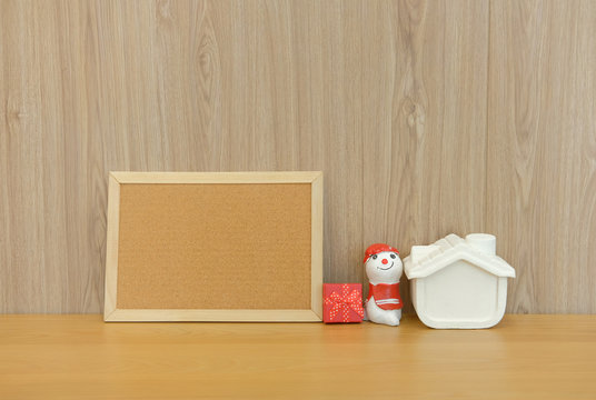 cork board snowman house miniature gift box on wooden desk table. christmas new year holiday