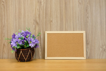 cork board purple artificial flower on wooden table at office