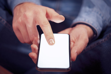 Man using mobile smart phone with dramatic lighting and shallow depth of field. Blank screen with bright lighting for design mockups.