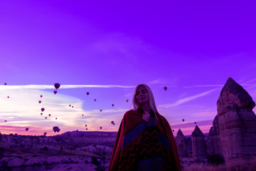magical dawn in Goreme Cappadocia Turkey. a girl in a canyon in traditional clothes surrounded by balloons in the rays of the rising sun