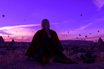 magical dawn in Goreme Cappadocia Turkey. a girl in a canyon in traditional clothes surrounded by balloons in the rays of the rising sun