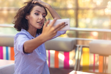 Young woman taking a selfie in coffee shop