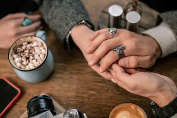 Man romantically holding woman hands on a cafe table