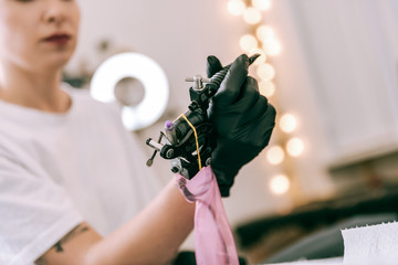 Female tattoo master holding special machine with her hands