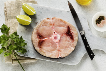 raw swordfish steak on a marble cutting board with olive oil and spices - obrazy, fototapety, plakaty