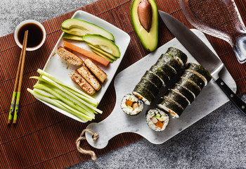 vegan ready-made sushi on the table in fish plates. rolls with fried tofu, cucumber, boiled carrots...