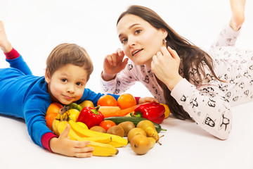 Fototapeta na wymiar Young mother eats fruit and vegetables with her young son, white background