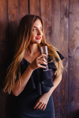 Obraz premium young attractive girl with a glass of champagne or wine on the background of the wall