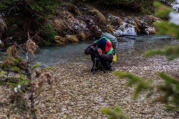 One Photographer is setting camera Close to the Mountain River