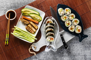 vegan ready-made sushi on the table in fish plates. rolls with fried tofu, cucumber, boiled carrots and fresh avocado. healthy vegan food