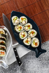 vegan ready-made sushi on the table in fish plates. rolls with fried tofu, cucumber, boiled carrots and fresh avocado. healthy vegan food