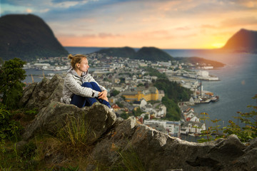 girl in Alesund is sitting alone on a mountain