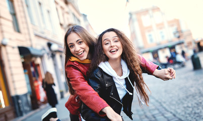 two young girls walking city, laughing and having fun. joyful Women in colored leather biker...