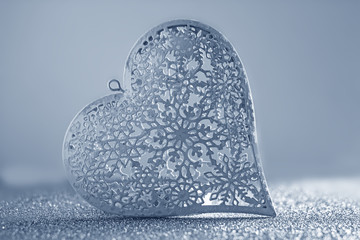 Valentines day background. White metal lacy heart on a silver background. Background about love,...