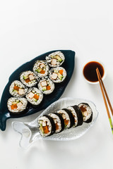 vegan ready-made sushi on the table in fish plates. rolls with fried tofu, cucumber, boiled carrots and fresh avocado. healthy vegan food