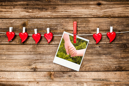 Red hearts and instant photo as two hands hold each other. Valentines Day card.