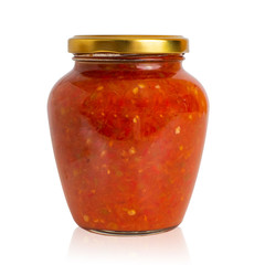 Spicy pepper tomato sauce adjika in a glass jar on white background