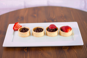 Small chocolate tarts with fresh strawberry on wood