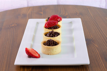 Small chocolate tarts with fresh strawberry on wood