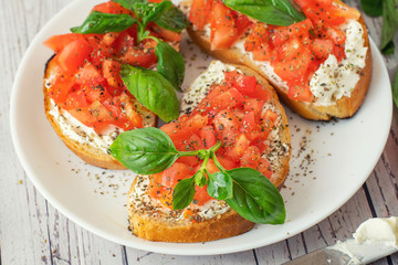 Traditional toasted Italian tomato bruschetta with spice and basil on white plate