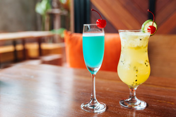 Turquoise color cocktail and passion fruit cocktail served with fresh cherry.