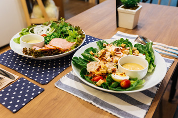Healthy Grilled Chicken Caesar Salad with Cheese, Croutons, Green Oak, Boiled Egg and Crispy Bacon. Served with Caesar Cream Dressing.