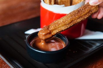 Traditional Spanish dessert Churros with sugar and cinnamon. Dipping in chocolate sauce.