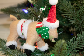 Dog in santa costume Christmas ornament on tree - with hat and scarf and poka dotted ears - selective focus