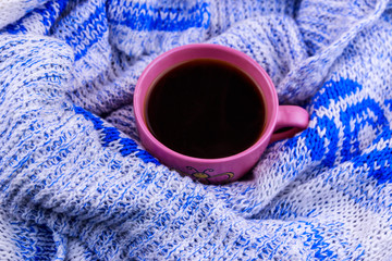 Cup of coffee on cozy knitted sweater