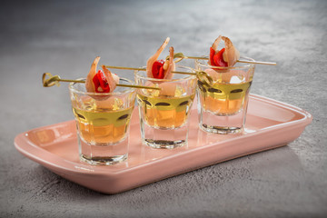 Close-up shot of three glasses of Golden tequila with tapas on skewers with dried meat, baked bell pepper and pine nuts.