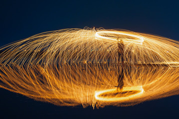 Showers of glowing sparks from spinning steel wool.fire Steel wool on salt field at after sunset blue hour,