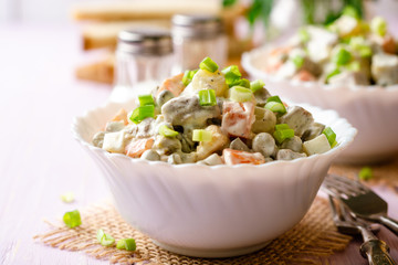 Traditional Russian salad Olivier in bowls on wooden table. Selective focus.