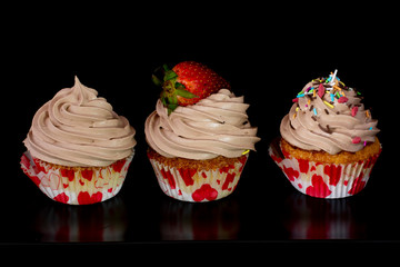 Fresh baked delicious different cupcakes served together with isolated black background