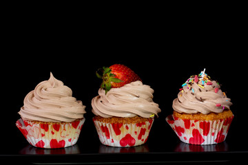 Fresh baked delicious different cupcakes served together with isolated black background
