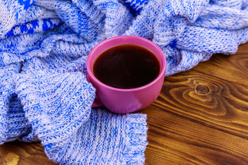 Obraz na płótnie Canvas Cup of coffee and cozy knitted sweater on wooden table