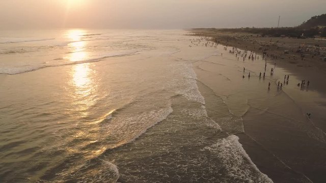sandy beach parangtritis near ocean with big waves, people in tropical resort at sunset. Yogyakarta, Indonesia. aerial view seascape, ocean and beautiful beach. Travel concept. Indonesia, jawa