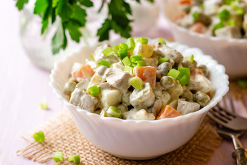 Traditional Russian salad Olivier in bowls on wooden table. Selective focus.