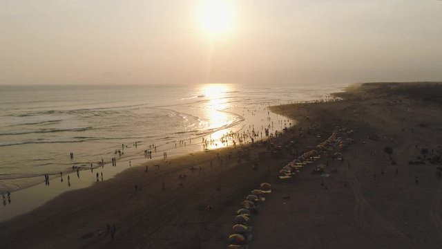 sandy beach parangtritis near ocean with big waves, people in tropical resort at sunset. Yogyakarta, Indonesia. aerial view seascape, ocean and beautiful beach. Travel concept. Indonesia, jawa