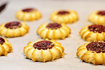 Homemade shortbread cookies with jam on cooking paper. Background