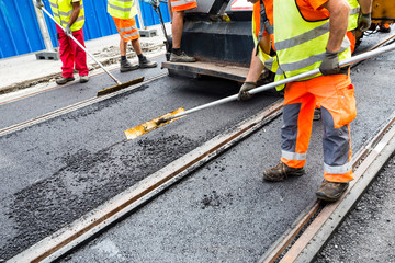 Workers construct asphalt road and railroad lines