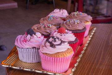 Fresh baked delicious different cupcakes served together with wood background