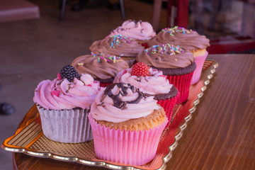 Fresh baked delicious different cupcakes served together with wood background