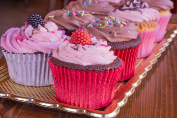 Fresh baked delicious different cupcakes served together with wood background