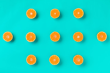 Fruit pattern of fresh mandarin slices on blue background. Flat lay, top view. Pop art design, creative summer concept. Half of citrus in minimal style. Tangerine.